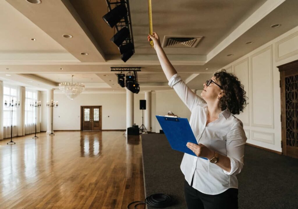 Planner measuring venue dimensions before wedding decor setup