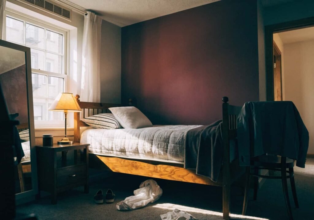 Burgundy accent wall behind bed in moody bedroom design