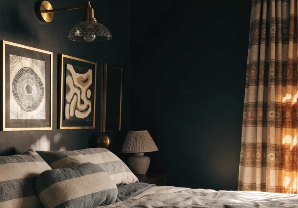 Black feature wall styled with gold frames and brass sconces for a luxury bedroom look.