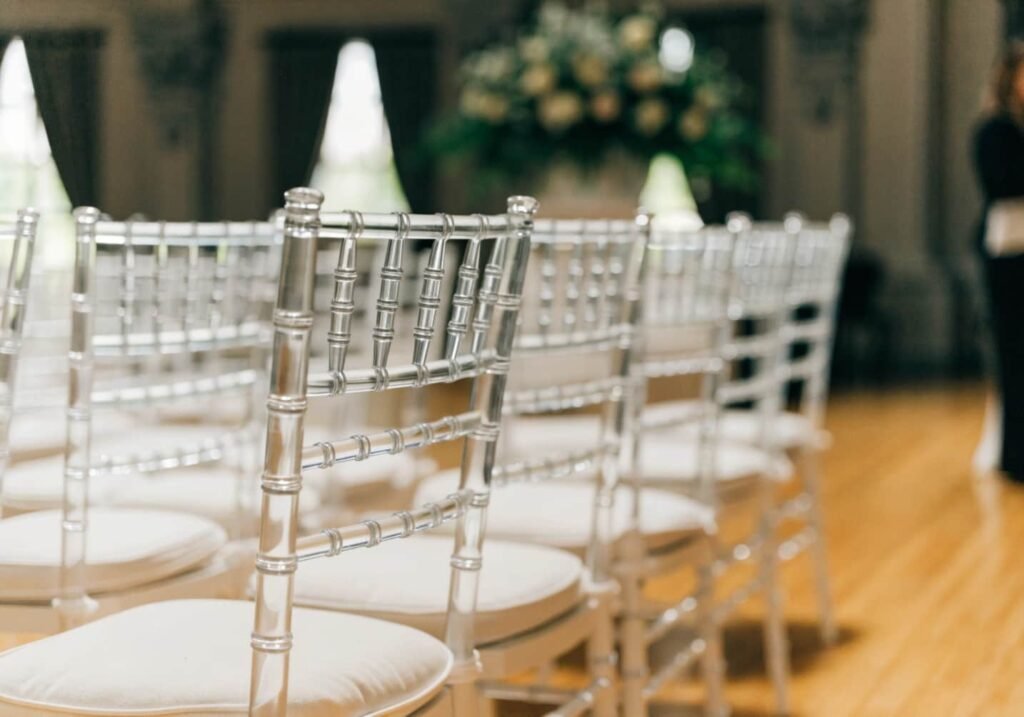 Rows of white chiavari chairs with cushions set up for wedding ceremony seating