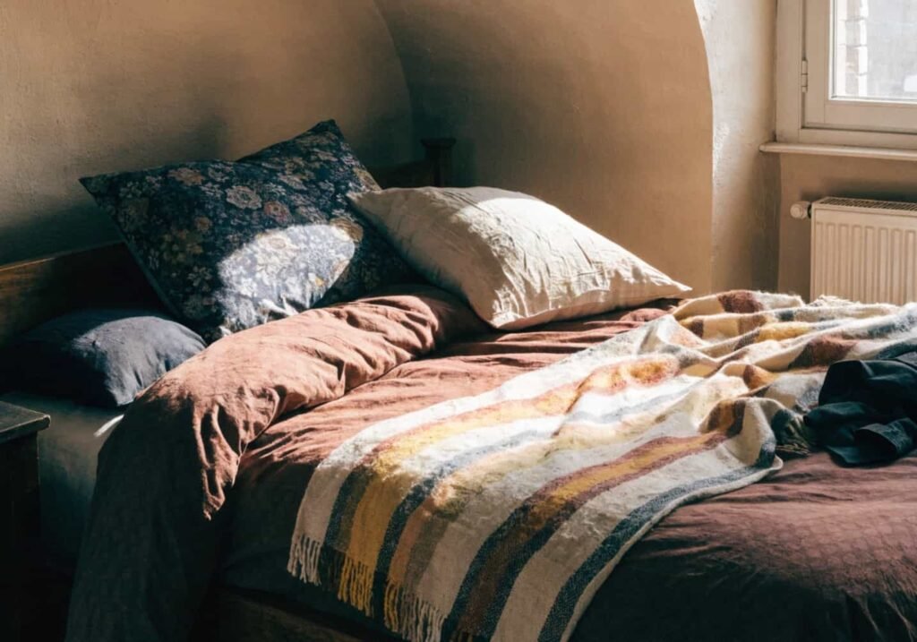 Layered luxurious bedding in a deep color palette for a moody bedroom