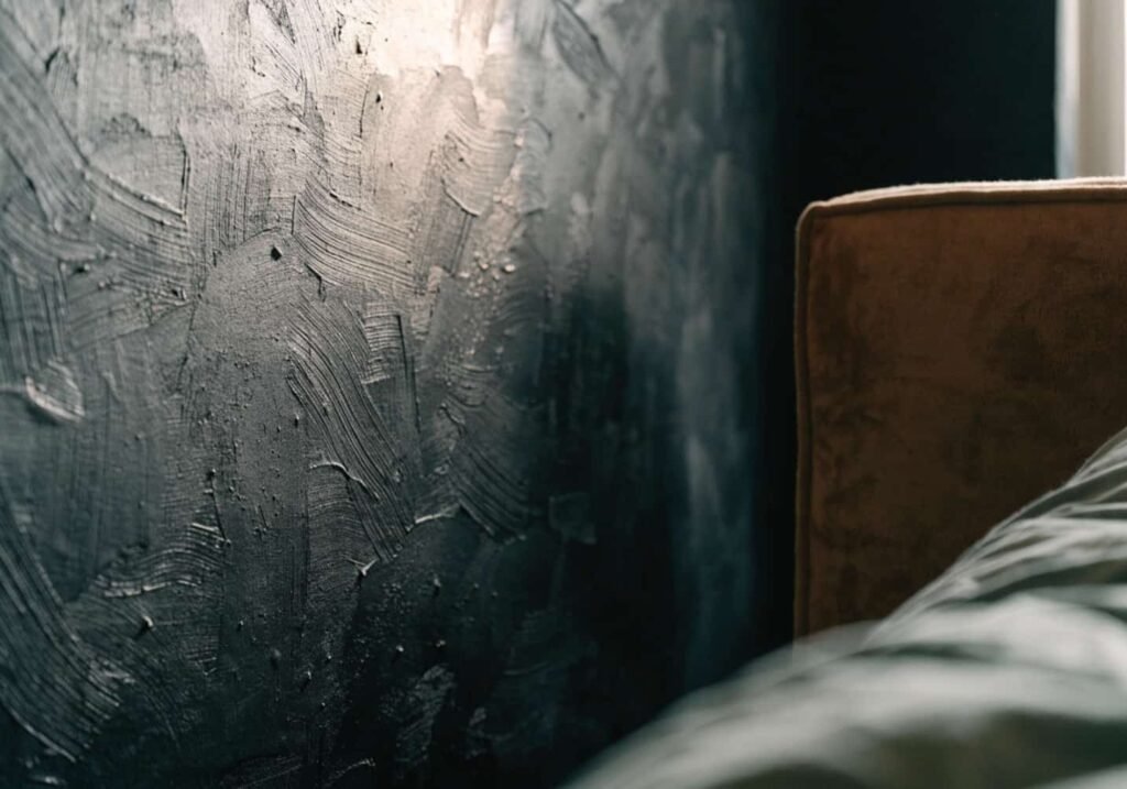 Close-up of a textured black plaster feature wall showing subtle depth and movement.