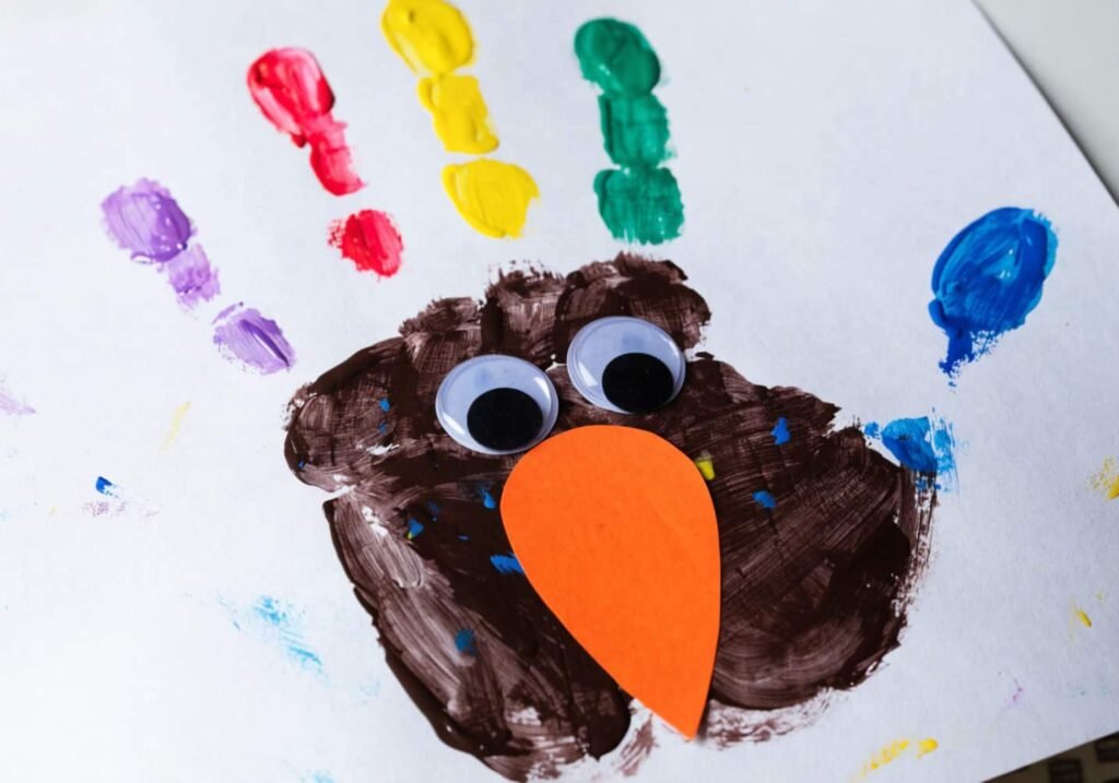Handprint turkey craft with colorful painted fingers as feathers and googly eyes.
