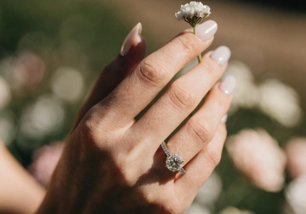Bridal manicure in glossy milky white on medium-length almond nails with an engagement ring.