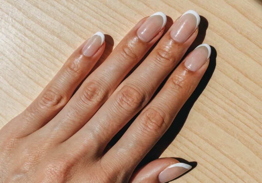 Modern micro French manicure with a thin white tip line on a sheer nude base.