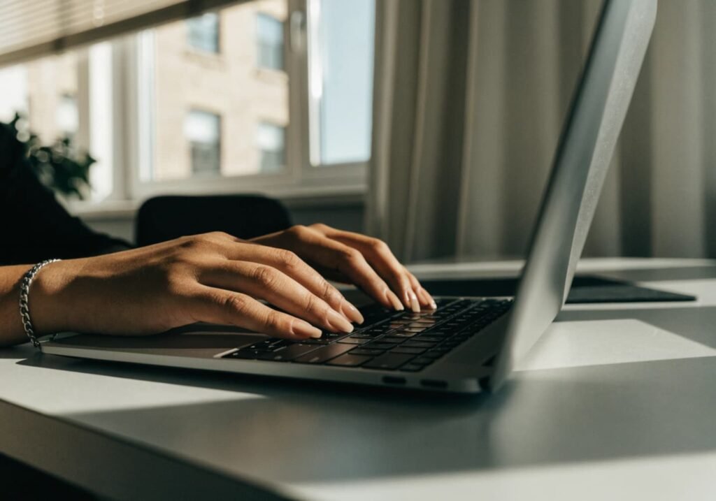 Office-appropriate sheer nude manicure while typing on laptop