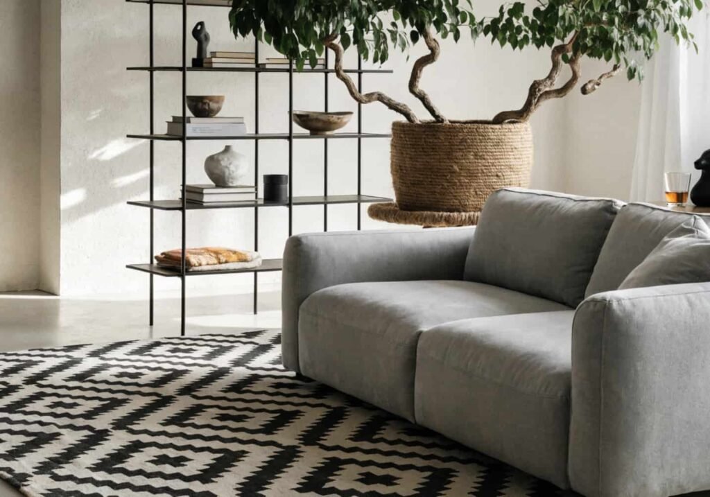 Modern boho grey couch with metal shelving and geometric rug