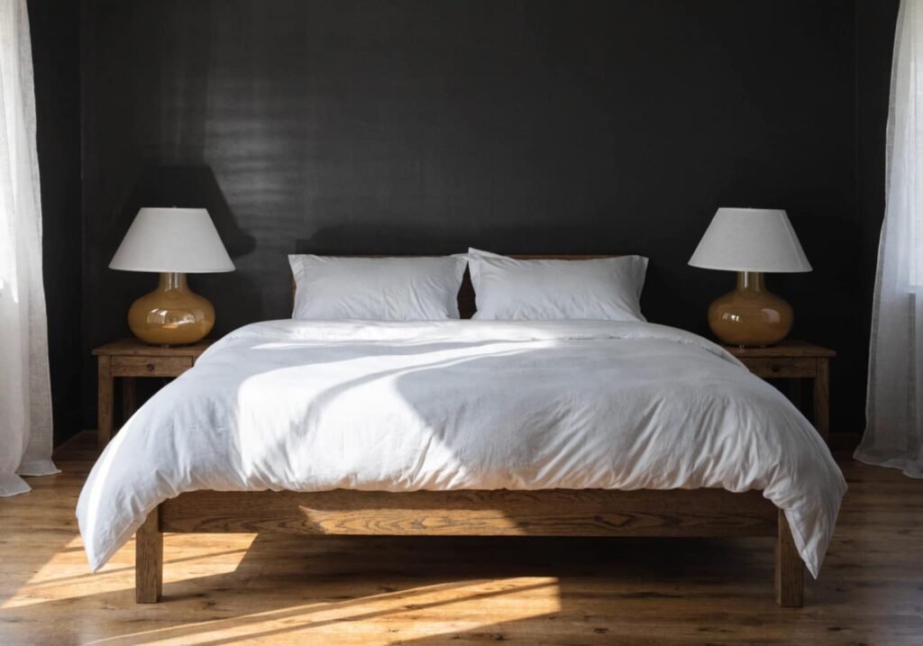 Symmetrical bedroom styling with matching lamps and nightstands against a black feature wall.