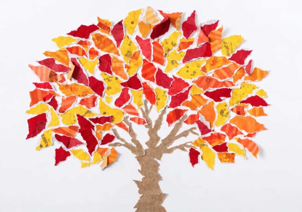 Fall tree collage craft made from torn red, orange, and yellow paper leaves.