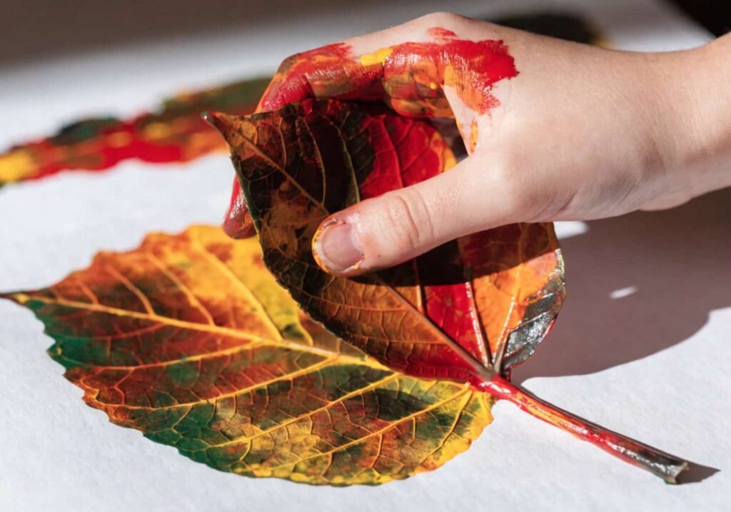 Child making a leaf print with paint during a kindergarten art project