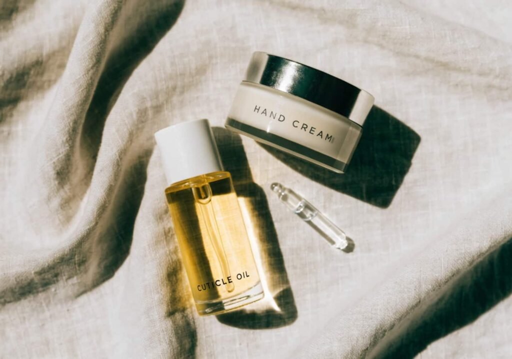 Luxury nail care products including cuticle oil and hand cream on neutral background