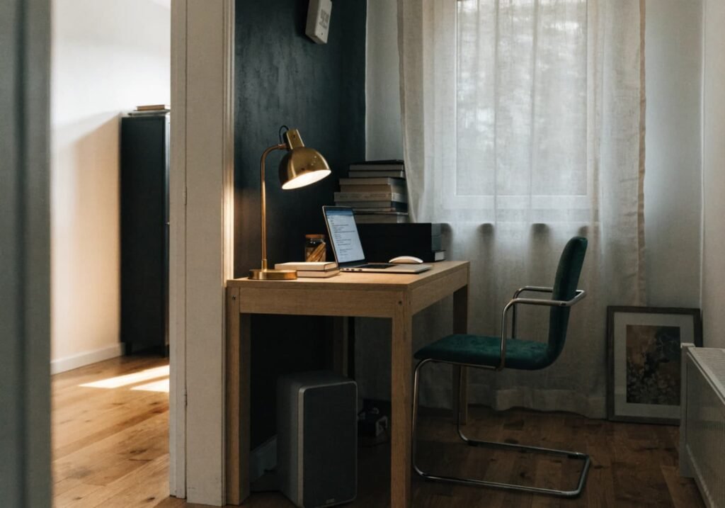 Black accent wall defining a home office nook against an otherwise soft white room.