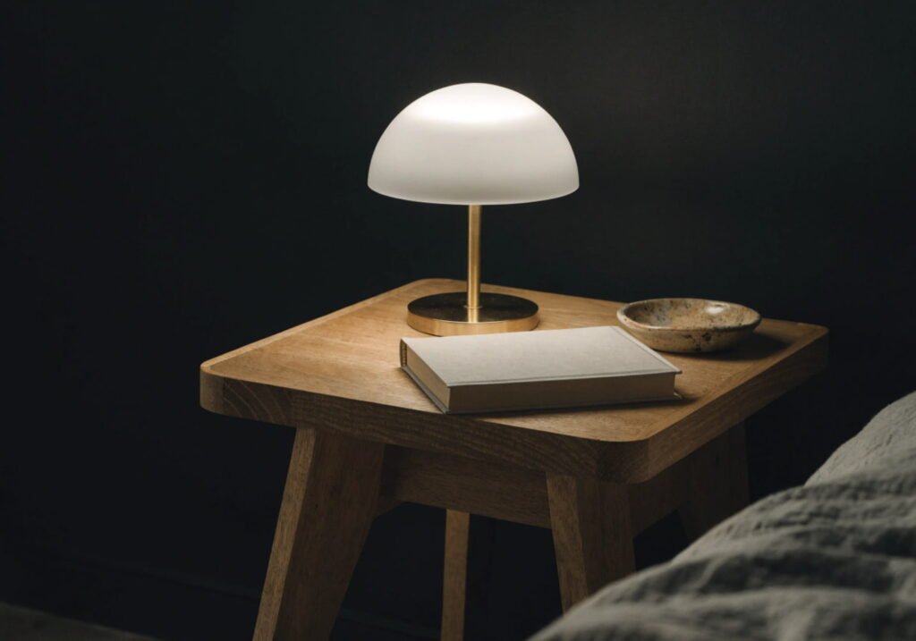 Minimalist wood nightstand styled simply against a black bedroom wall for a grounded look