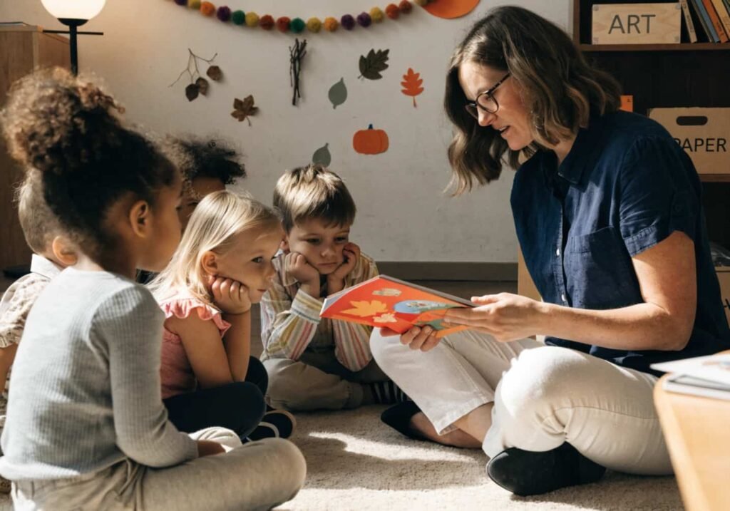Teacher reading a fall-themed picture book to kindergarten students on a classroom rug.