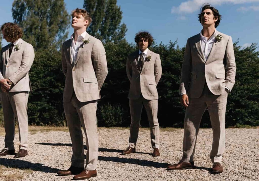 Groomsmen in lightweight taupe linen suits suited for a hot outdoor summer wedding.