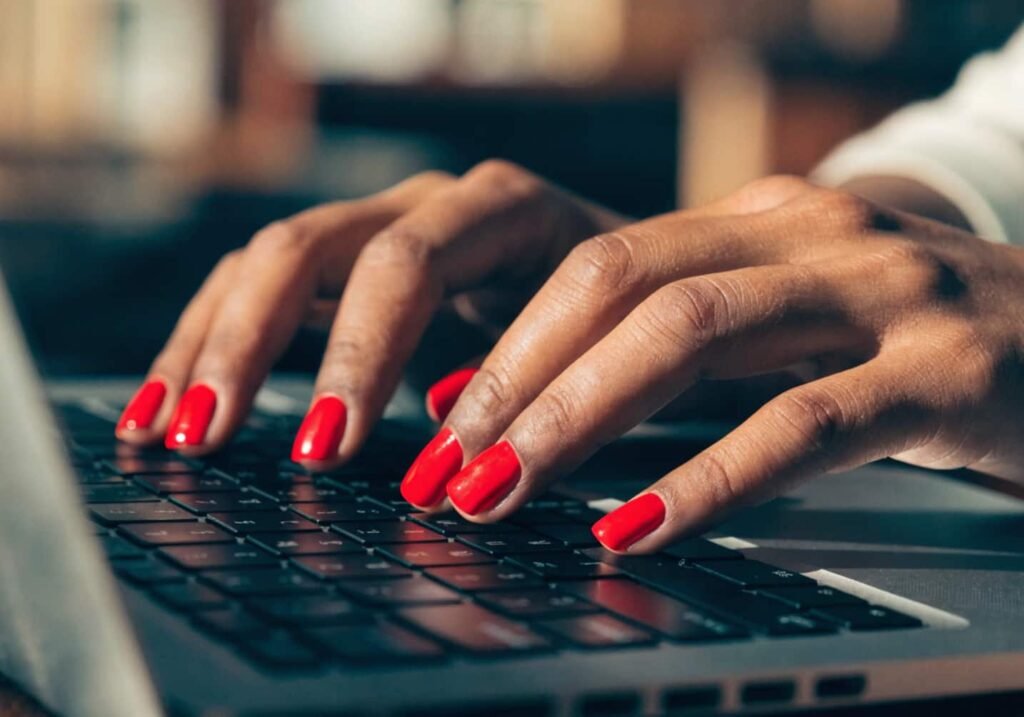 Square shape acrylic nails in red, shown while typing on a keyboard.