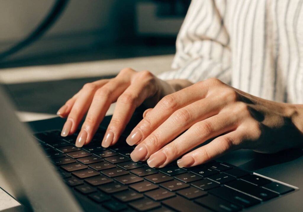 Everyday elegant gel manicure in rounded square shape shown while typing on a laptop.