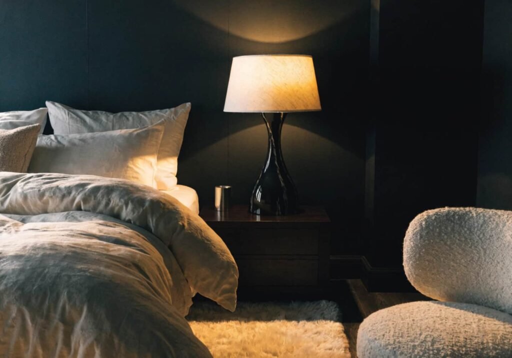 Cozy bedroom combining a black feature wall with warm bedding and soft lighting.