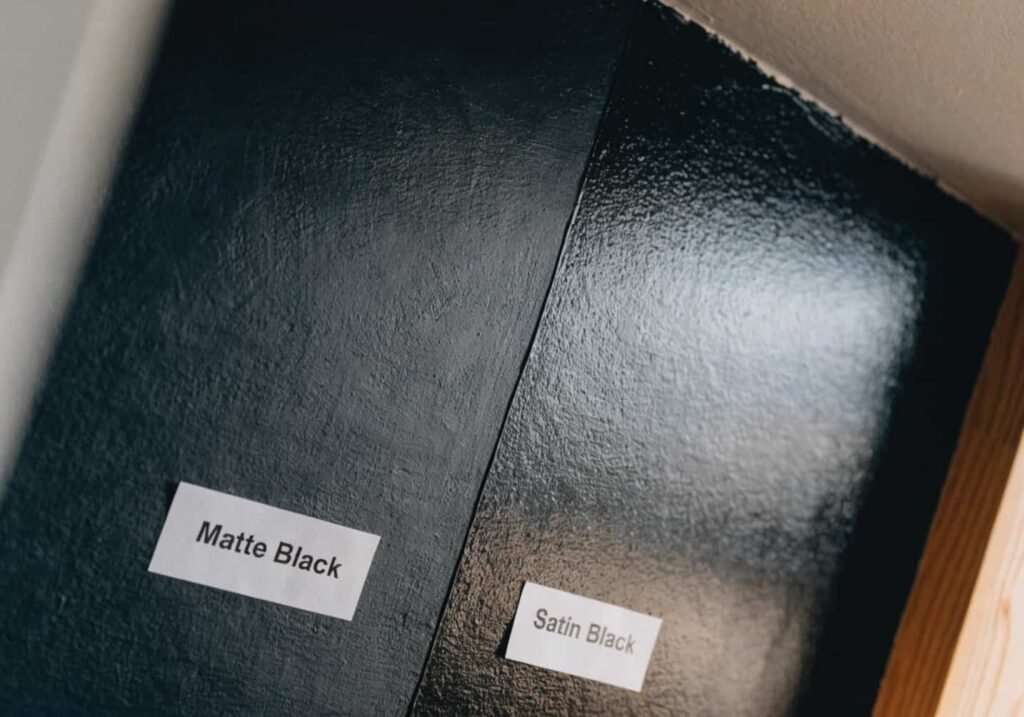 Close-up comparison of matte and satin black paint finishes on a bedroom wall