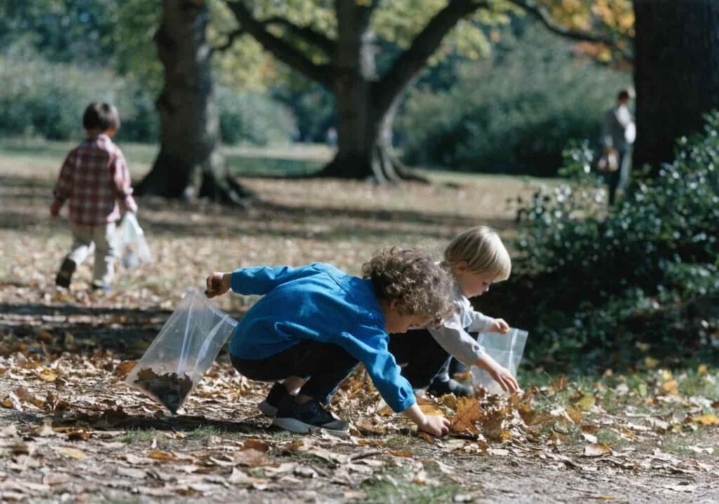 Kindergarten students on a fall nature walk collecting leaves and acorns in bags.