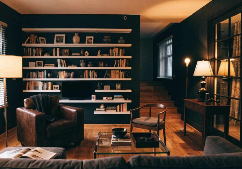 Black accent wall with built-in white floating shelves used for books and decor storage.