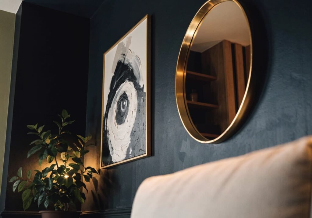Framed art and a plant standing out beautifully against a black accent wall