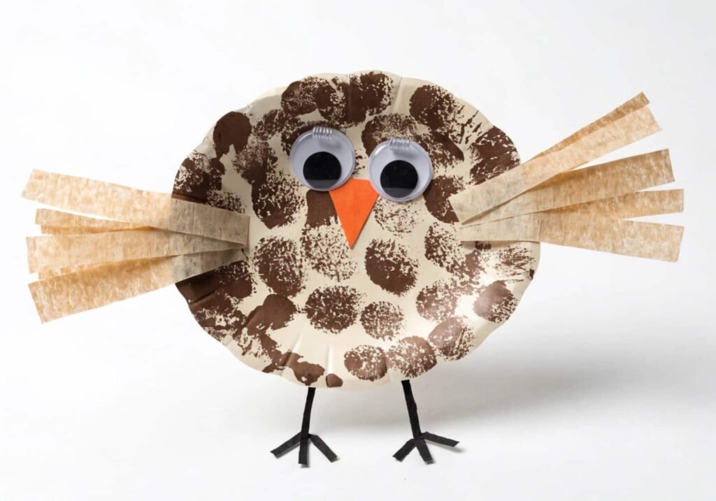 Paper plate owl craft with big eyes and textured brown feathers.
