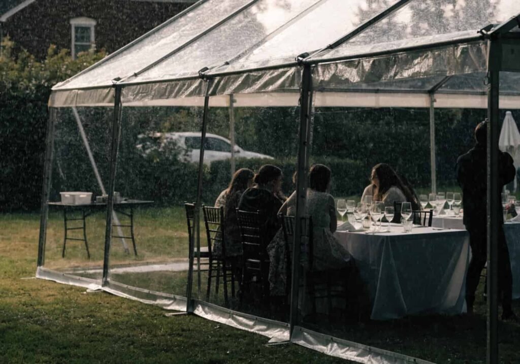 Tented backup space prepared for rainy weather at a backyard wedding reception.
