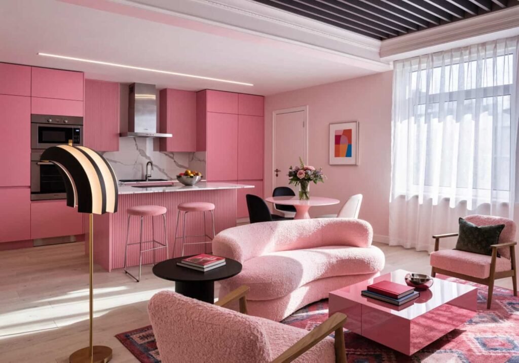 A living room with three painted pink test swatches on a white wall next to natural window light, soft daytime photography style.