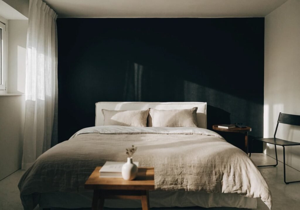 Bedroom designed around a black accent wall as its main anchor point.