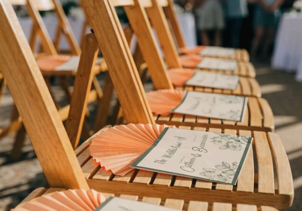 Wedding programs used as fans placed on guest chairs for ceremony comfort