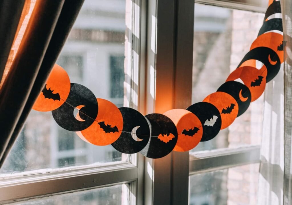 Handmade orange and black paper chain garland with cutout bat and moon shapes.