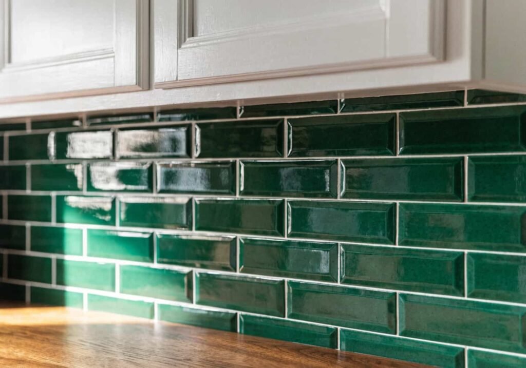 Forest green subway tile backsplash in a kitchen with white cabinets.