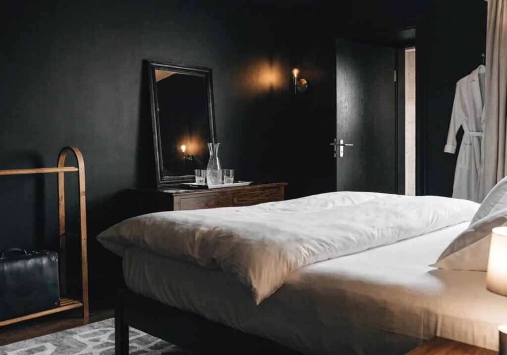 Boutique hotel styled black bedroom with a luggage rack and water tray on the dresser