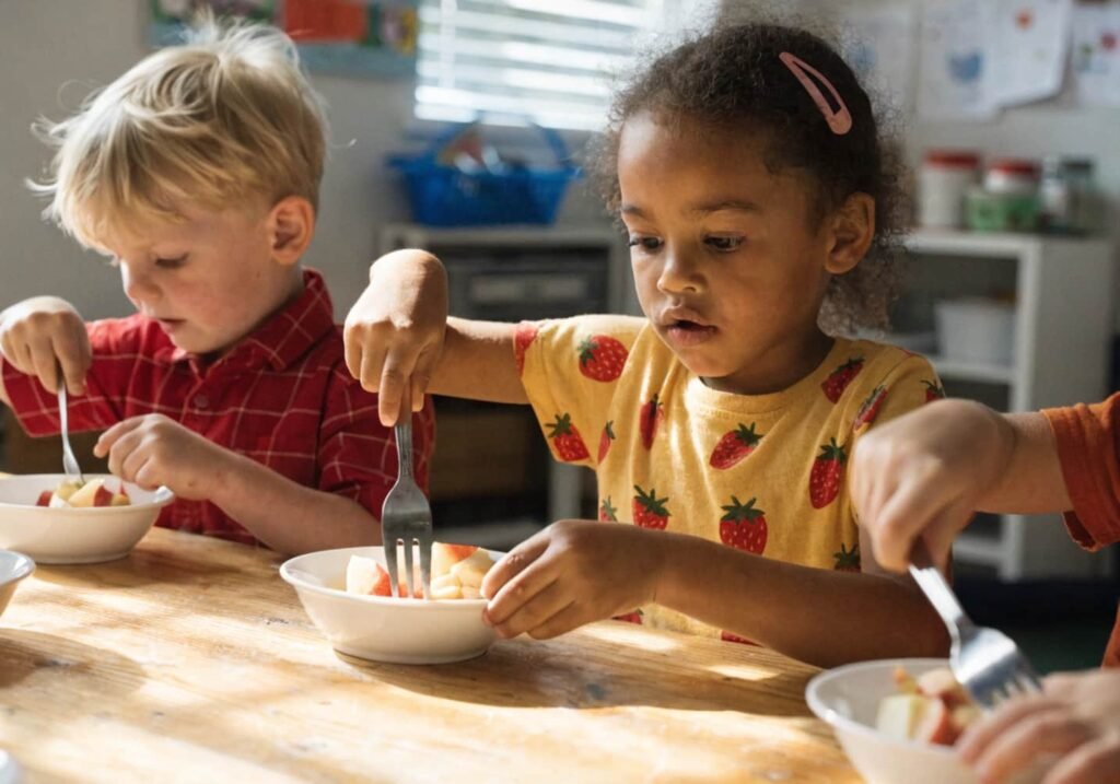 Kindergarten cooking activity with children mashing apples for homemade applesauce