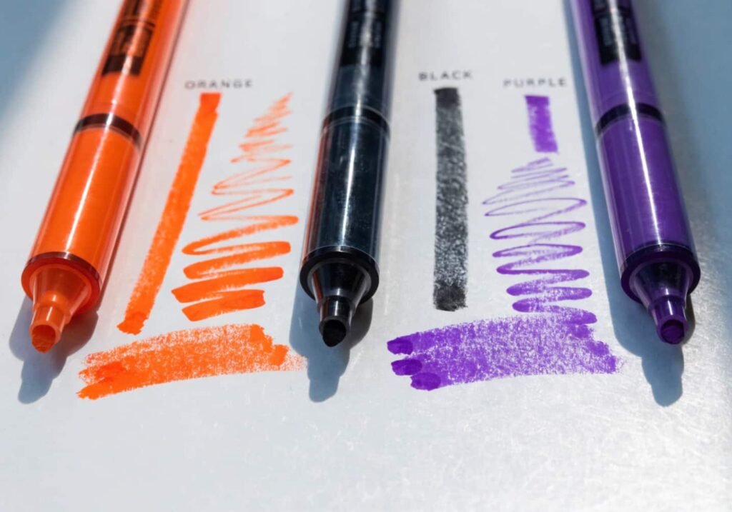 Orange, purple, and black dry erase markers arranged for a Halloween board design.