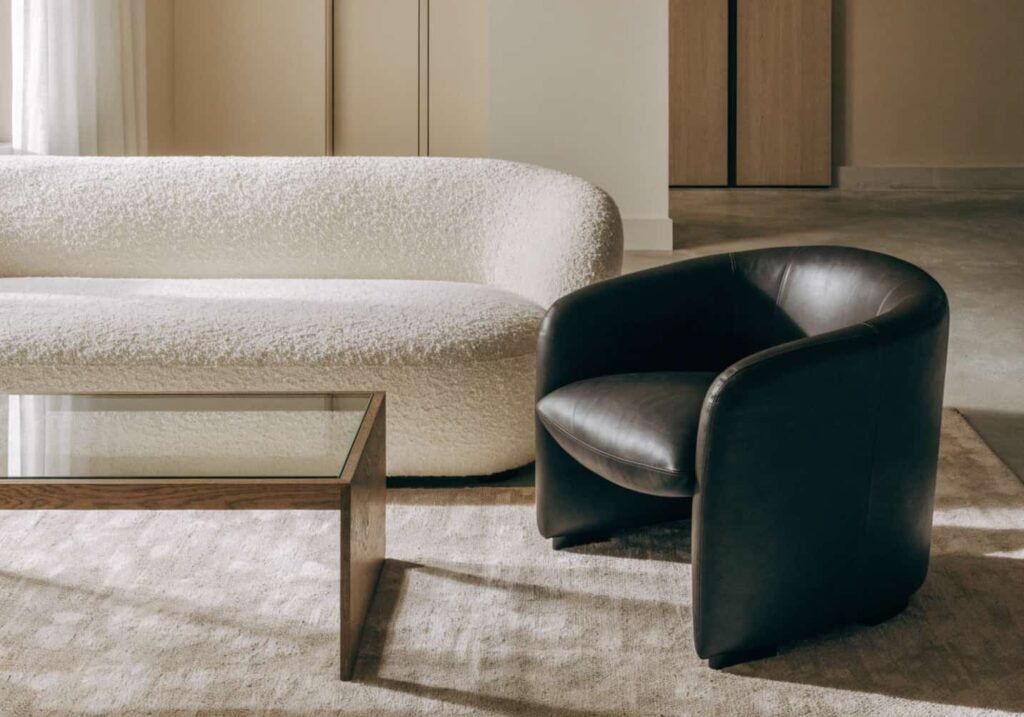 Modern living room furniture mixing boucle, wood, glass, and leather textures.