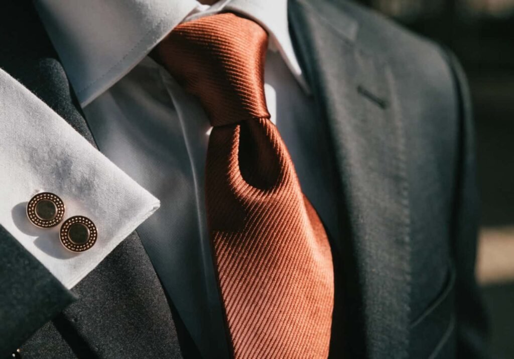 Rust-colored tie and cufflinks used as an accent against a charcoal wedding suit.