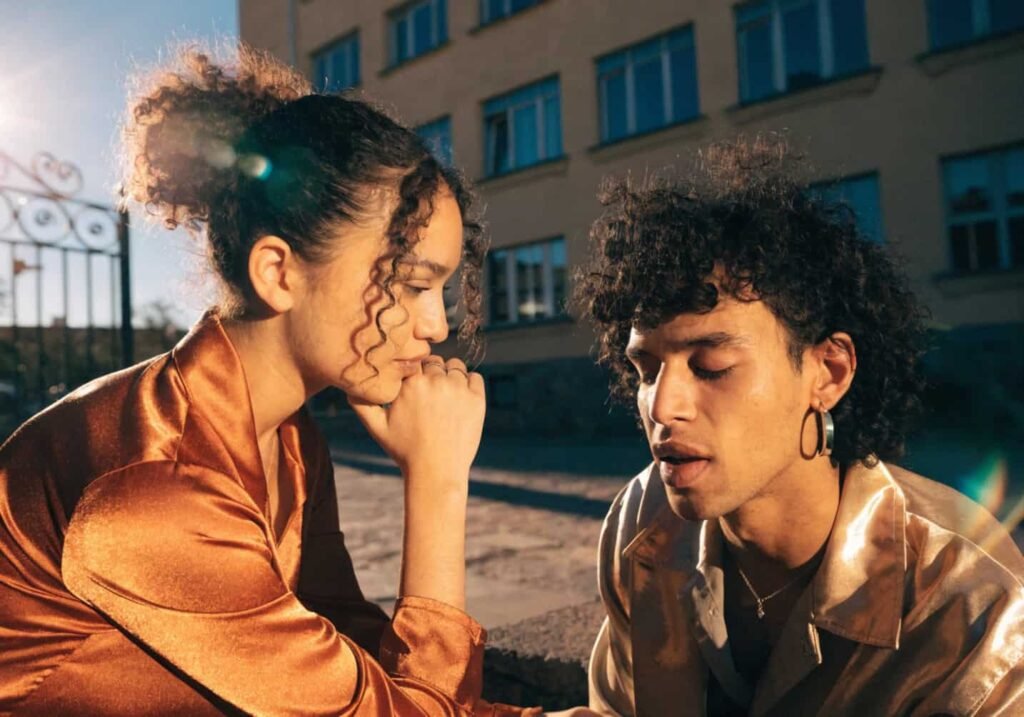 A couple photographed in golden hour light wearing warm terracotta and gold wedding attire.