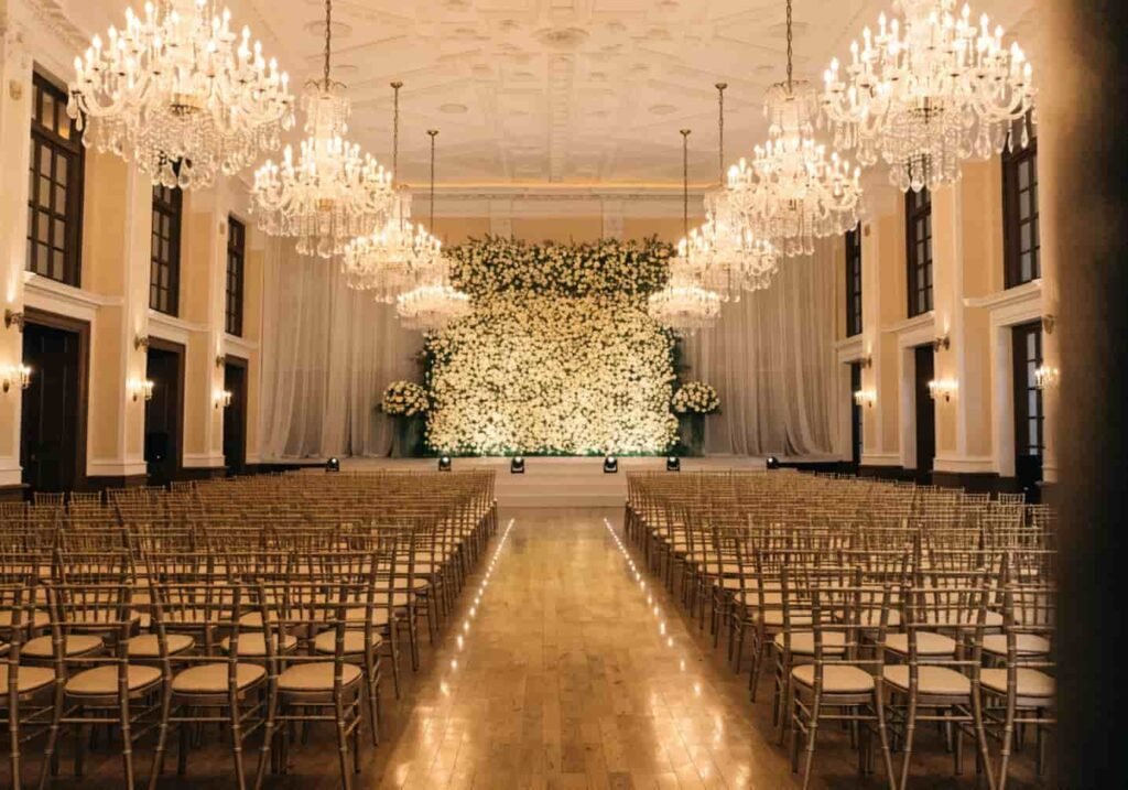 Chandelier-lit indoor wedding venue set up for a ceremony with gold chairs.