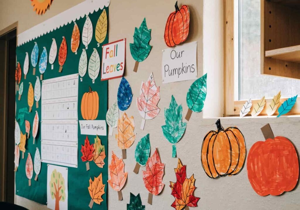 Classroom bulletin board displaying children's handmade fall crafts and drawings