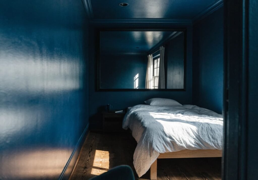 Small room painted in a single dark colour with mirror reflecting light for depth