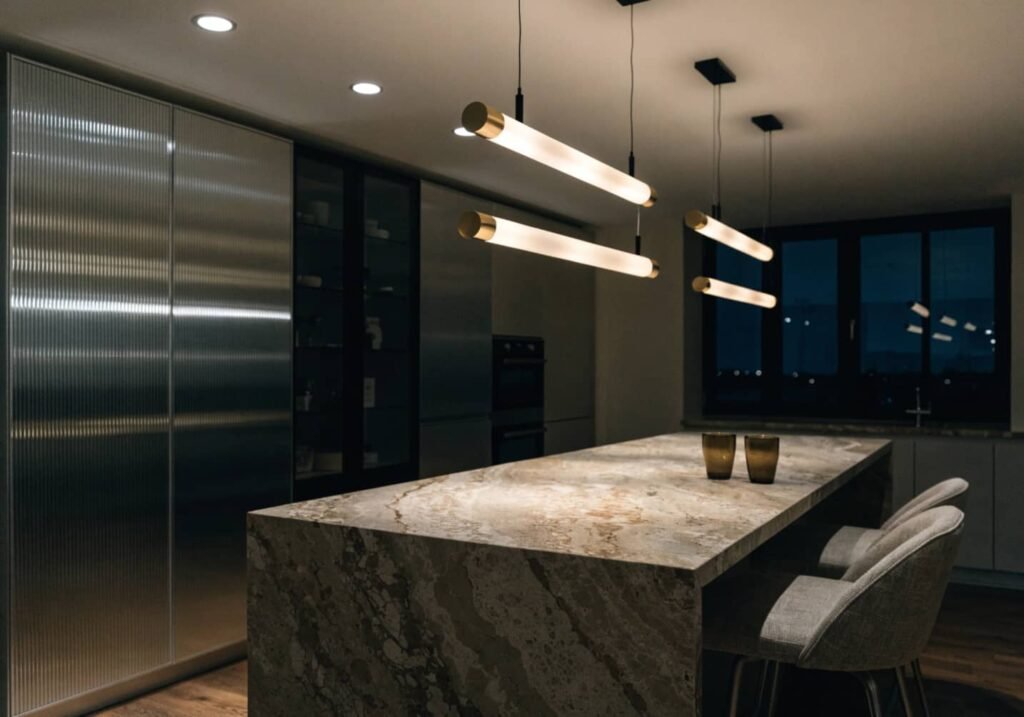 Modern pendant lighting layered with recessed lighting over a kitchen island.