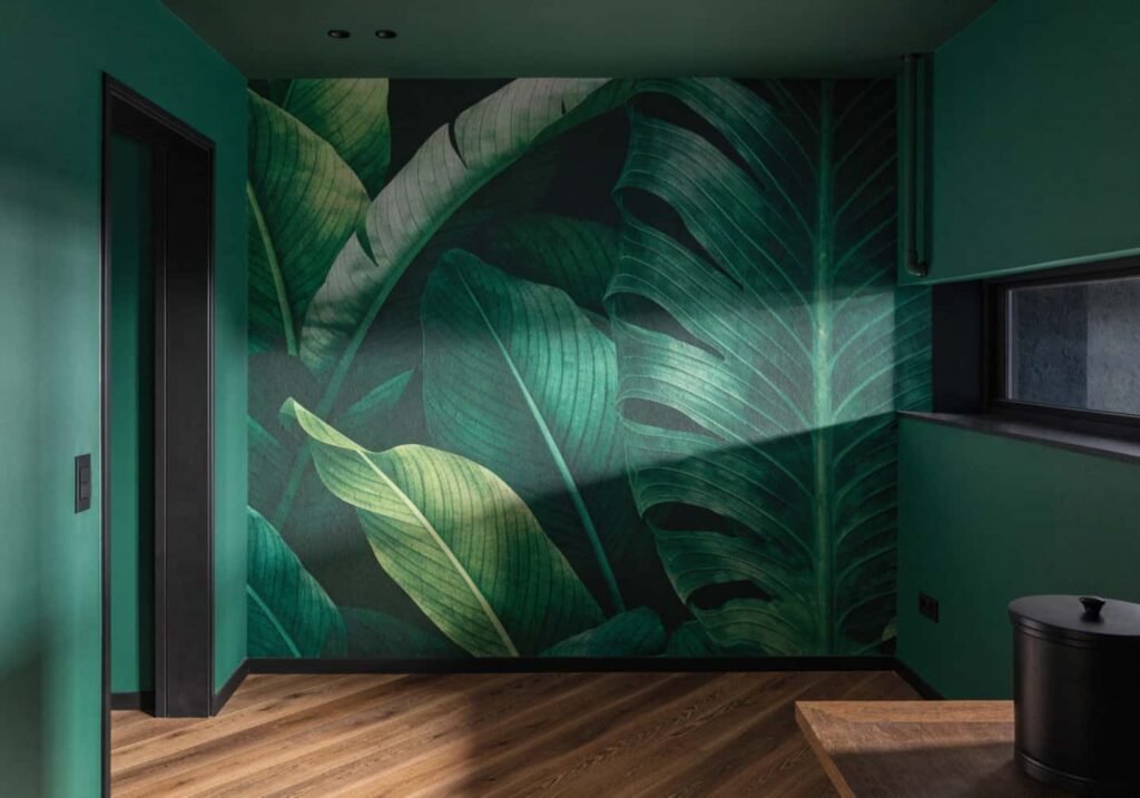 Botanical leaf-print wallpaper feature wall with coordinating solid green walls.
