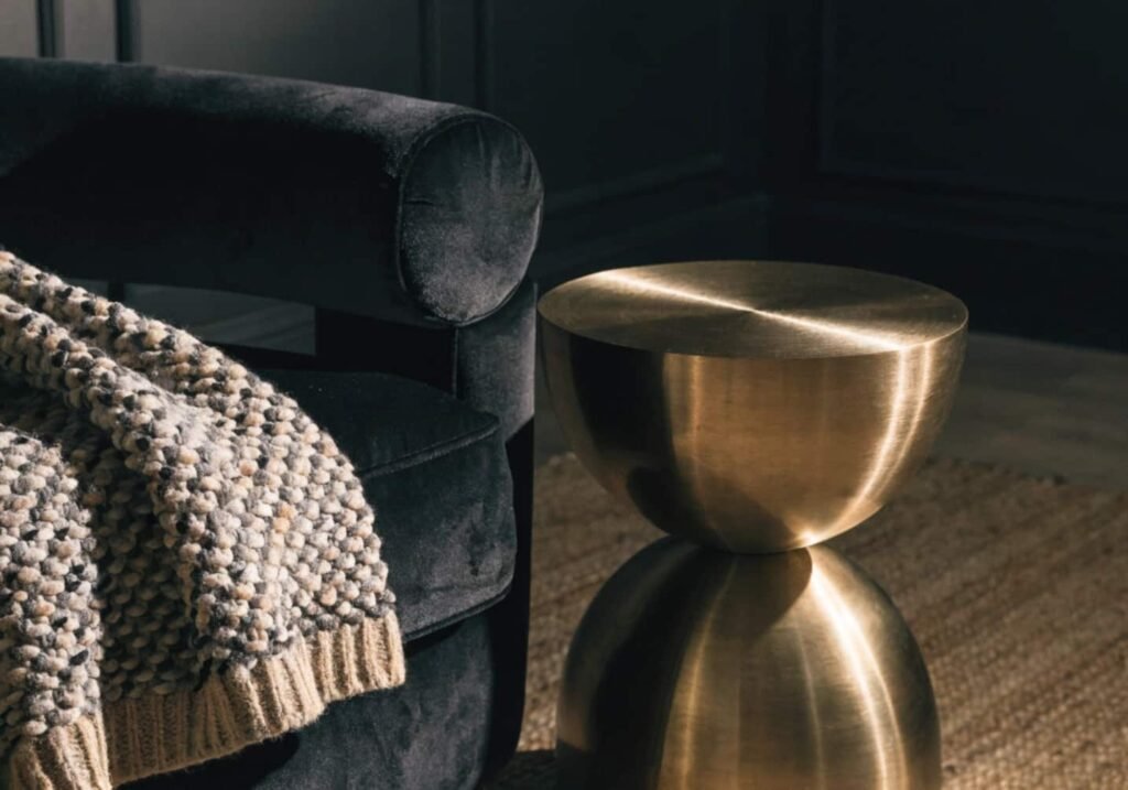 Mixed textures — velvet, knit, jute, and brass — layered in a dark room