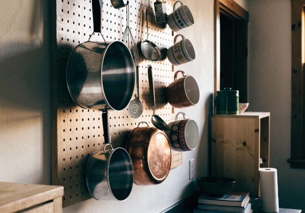 Kitchen pegboard wall storage holding pots, mugs, and utensils