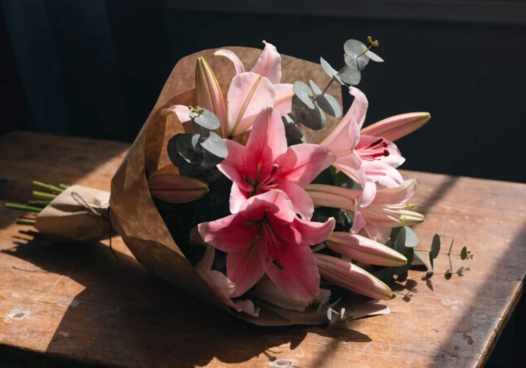 Pink-toned lily bouquet with eucalyptus greenery wrapped in kraft paper