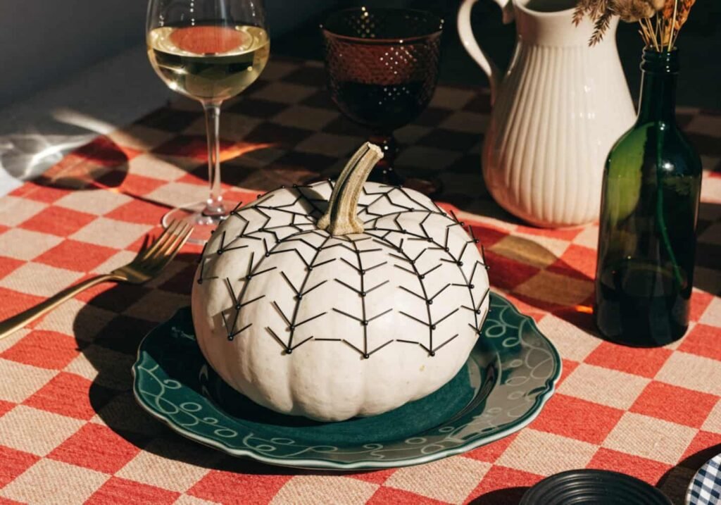 No-carve pumpkin decorated with black thumbtacks arranged in a spiderweb pattern.