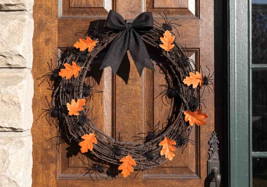DIY grapevine Halloween wreath decorated with a black bow and small spiders.
