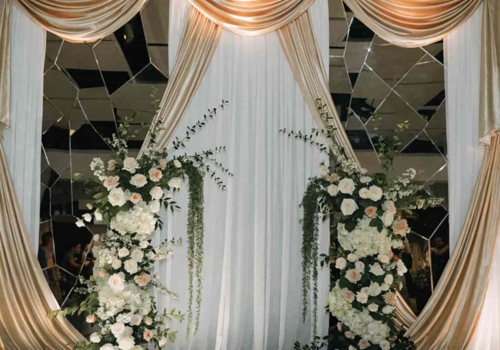 Layered drapery and mirror decor elevating an indoor wedding stage.
